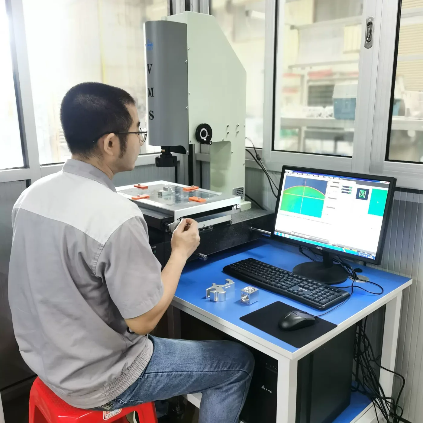 Inspector measuring machined aluminium parts on the video measuring system
